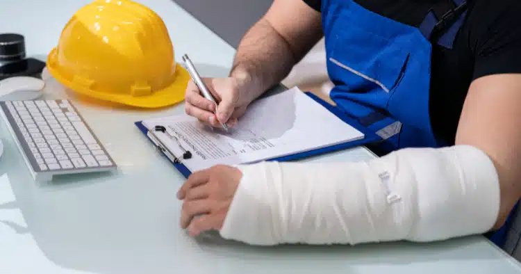 NJ Construction Accident Injured construction worker with arm cast filling out legal paperwork for workplace injury claim